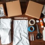 Materiały potrzebne do zrobienia stroju astronauty rozłożone na stole, w tym kartony, folia aluminiowa, taśma i plastikowe butelki